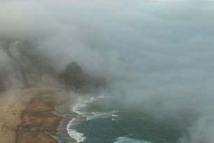 an aerial view of a beach and ocean covered in clouds