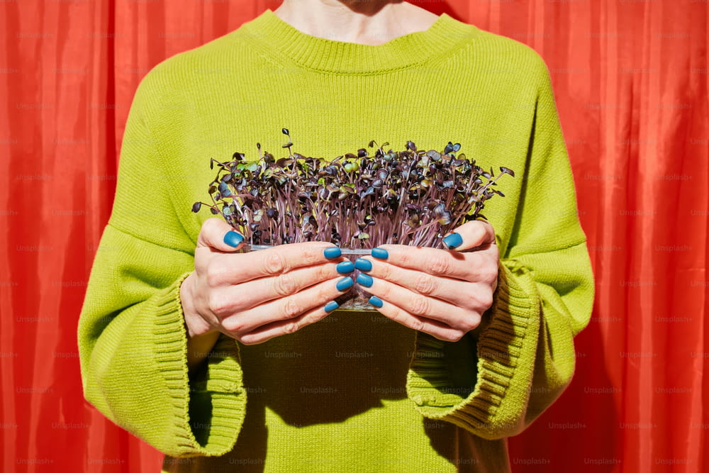 a woman holding a bunch of plants in her hands