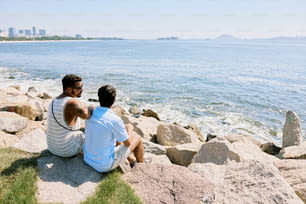 duas pessoas sentadas em rochas perto da água