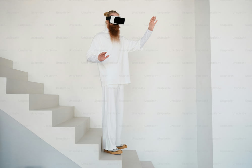 a man with a long beard wearing a white outfit standing on a set of stairs