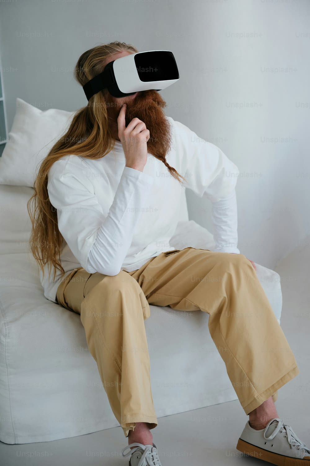 흰 셔츠와 황갈색 바지를 입고 소파에 앉아 있는 여성