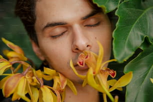 a man smelling a flower with his eyes closed