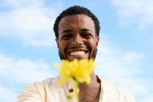 un homme souriant et tenant une fleur dans sa main