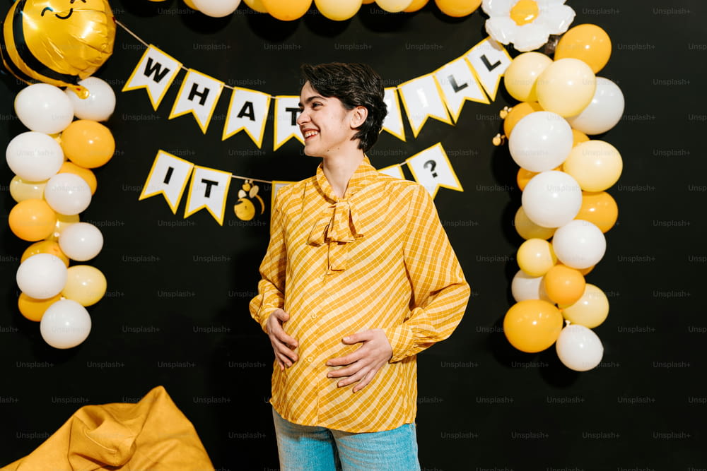 a pregnant woman standing in front of a balloon arch