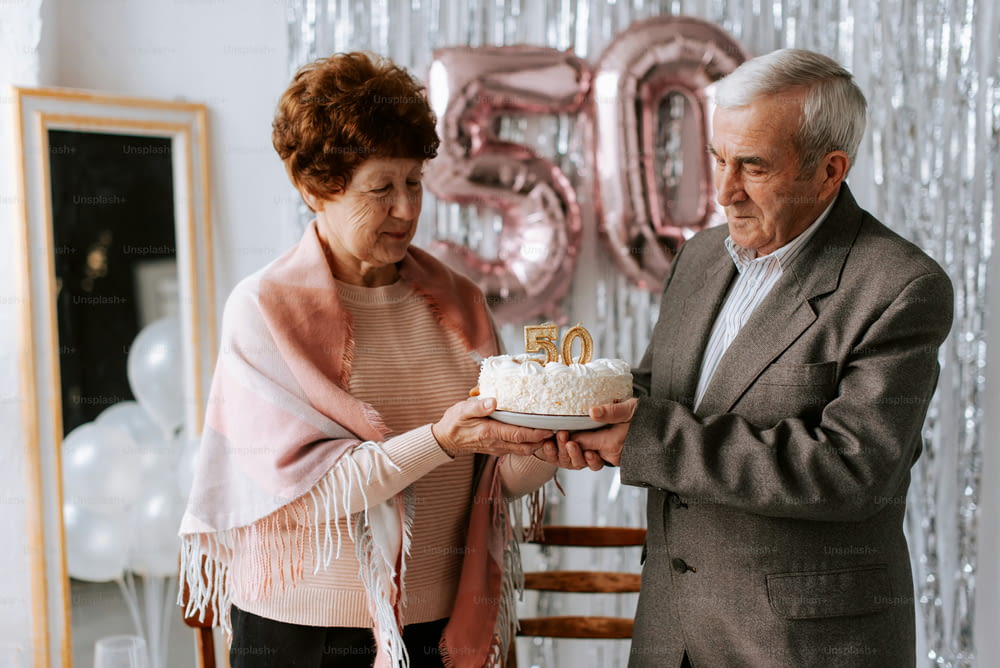 a man and woman holding a cake with the number 50 on it