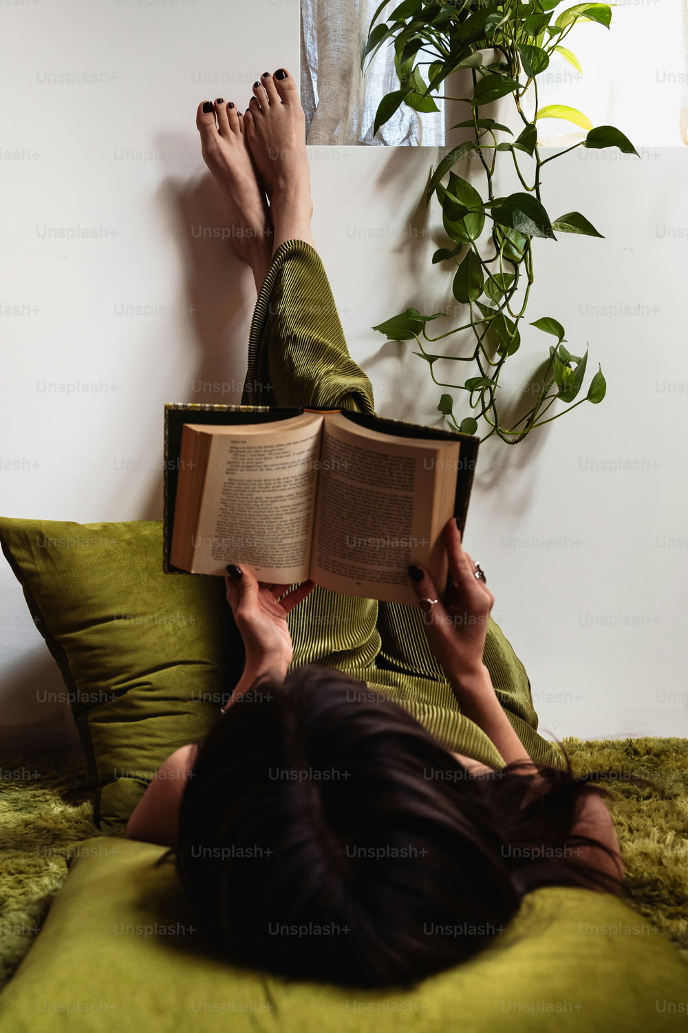 ベッドに横たわって本を読む女性