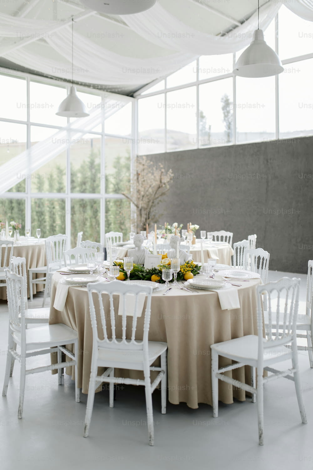 uma mesa montada com cadeiras brancas e flores amarelas