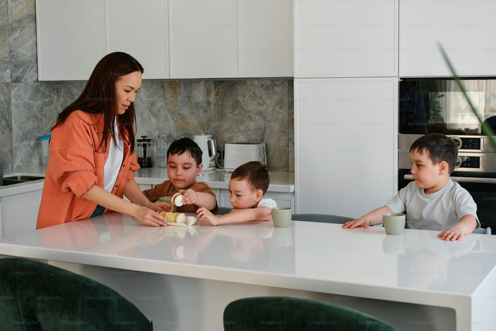 a woman standing over a kitchen counter with three children