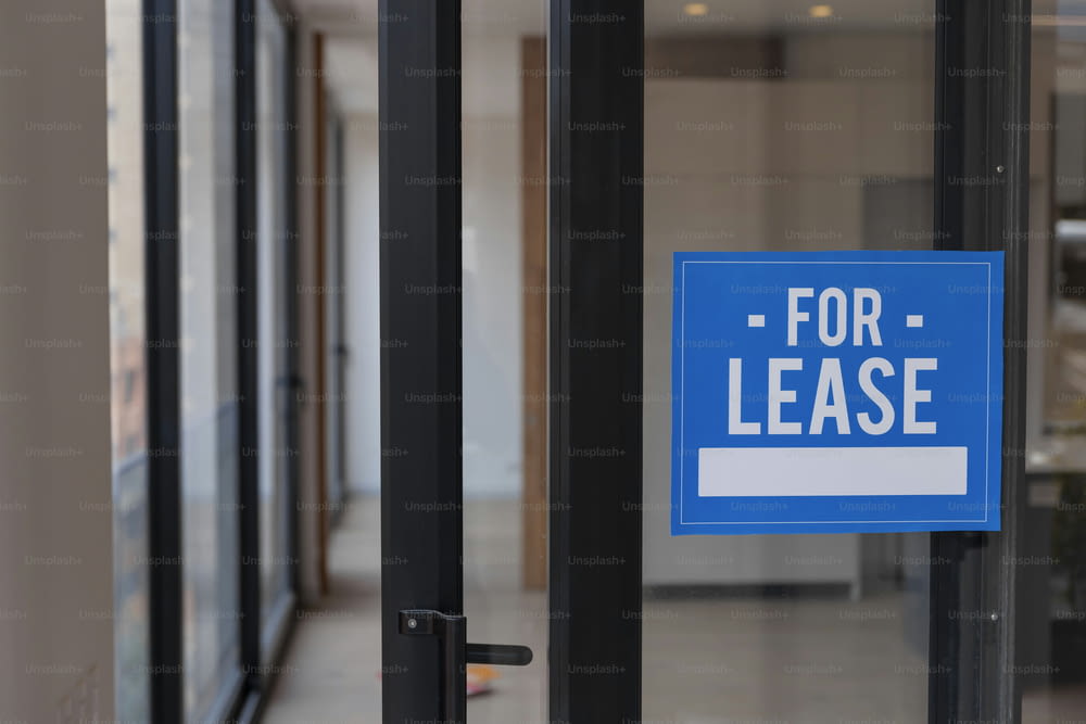 a blue for lease sign hanging on a glass door