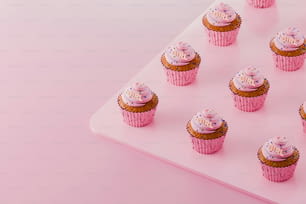 ein Tablett mit Cupcakes mit rosa Glasur