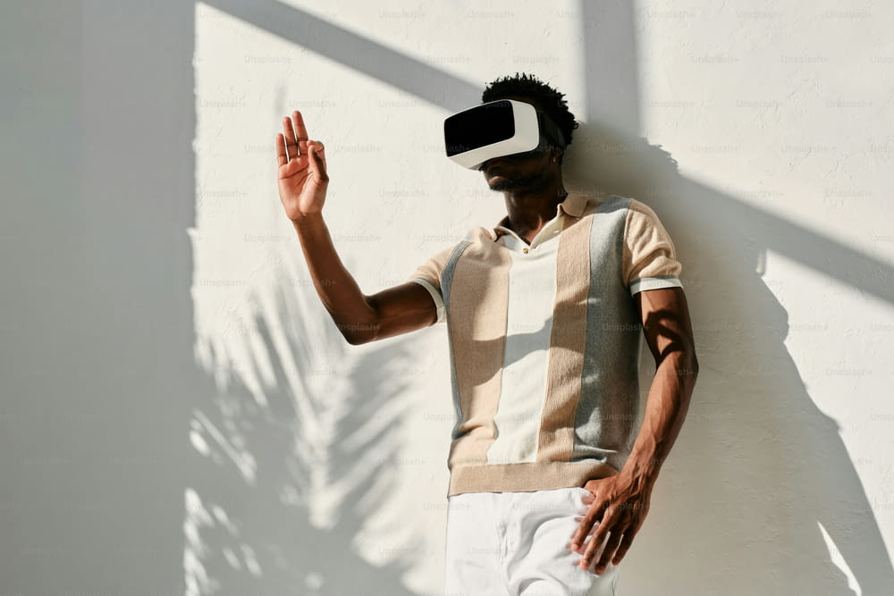 a man wearing a virtual reality headset standing against a wall