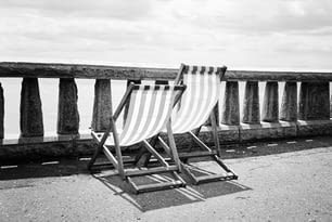 um par de cadeiras de gramado sentado em cima de uma praia