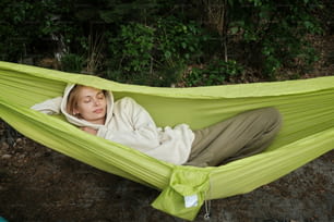 a woman laying in a green hammock with her eyes closed