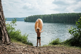 a young boy holding a surfboard over a body of water