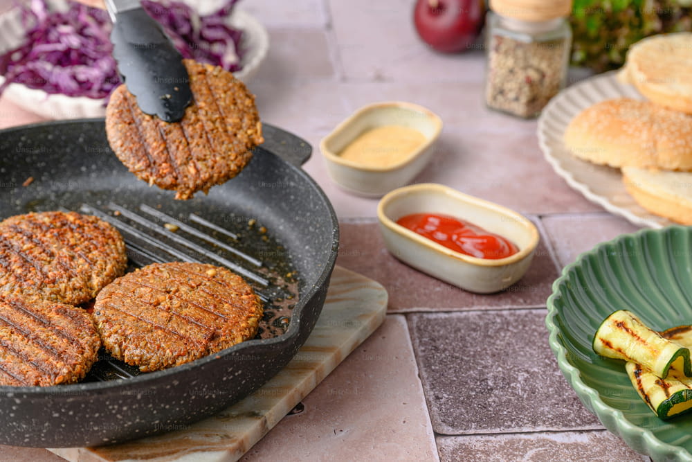 hamburgers being cooked in a frying pan on a table