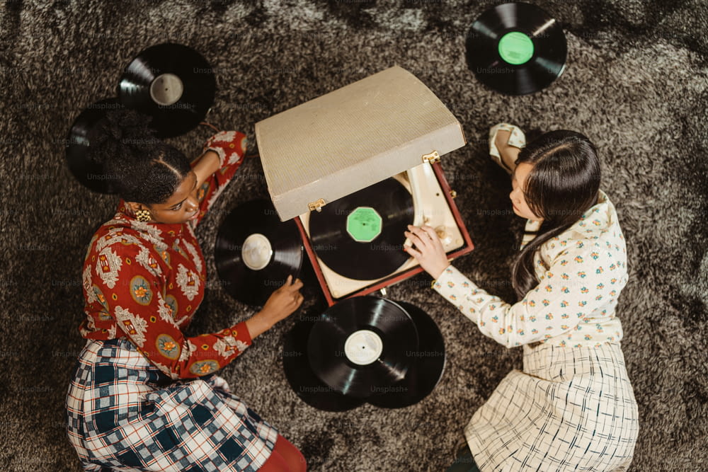 deux femmes assises sur le sol jouant avec un tourne-disque