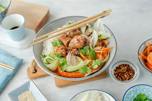 Un bol de nourriture asiatique avec des baguettes sur le côté