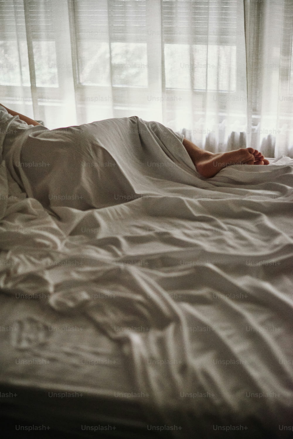 a person laying in a bed with white sheets