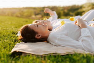 a woman laying in the grass with a flower in her hand