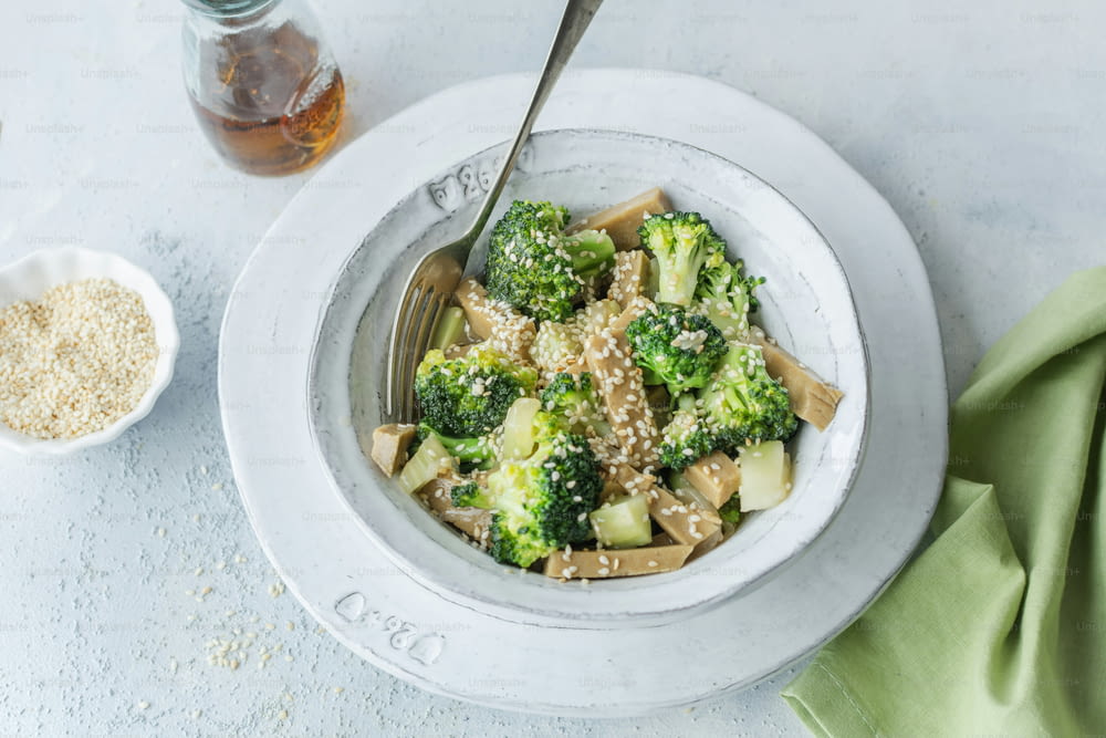 a bowl of broccoli with sesame seeds and a spoon