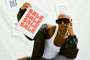 a woman holding up a sale sign and a pair of sunglasses