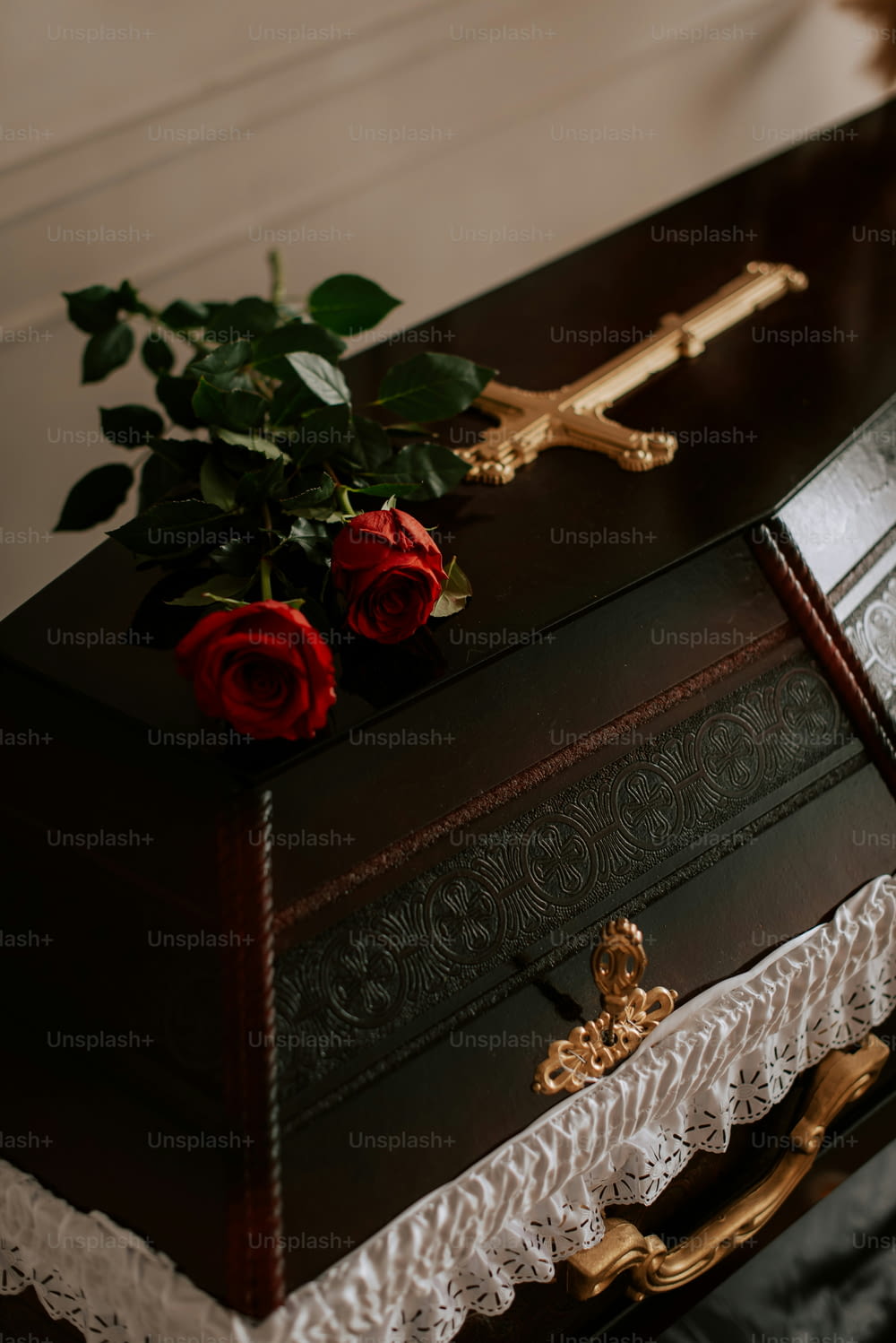 una scatola di legno con sopra una croce e delle rose