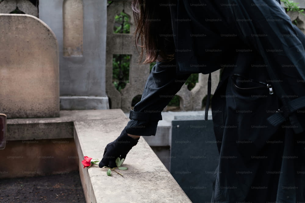 a person placing a flower on a grave