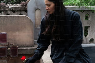 a woman places a rose in a grave