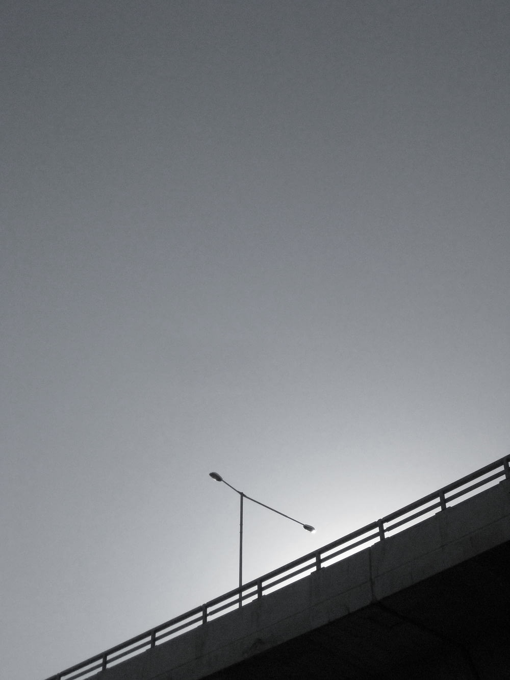 grayscale photo of bridge with postl ight