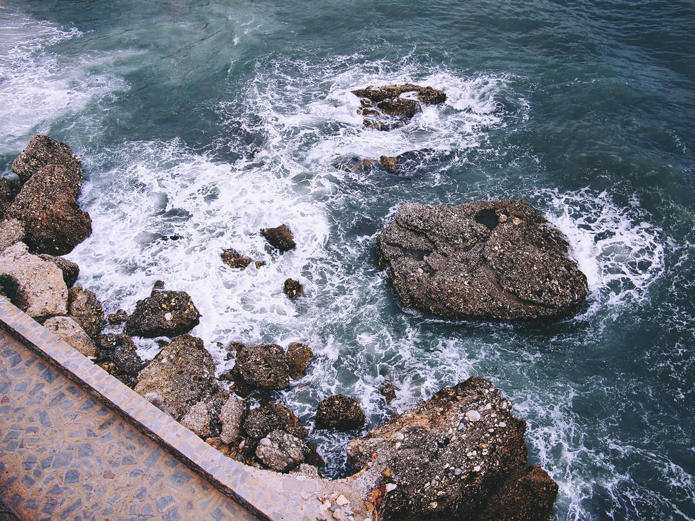 rock formations with crashing seashore at daytime